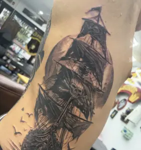 Black and grey pirate ship rib tattoo by Moose, Calgary Tattoo Company