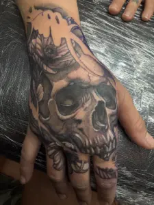 Black and grey skull and flower hand tattoo by Moose, Calgary Tattoo Company