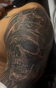 Black and grey skull with a crown shoulder tattoo by Moose, Calgary Tattoo Company